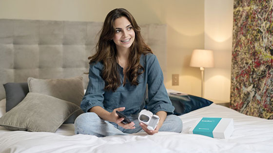 A patient in braces at home with the ScanBox and their phone
